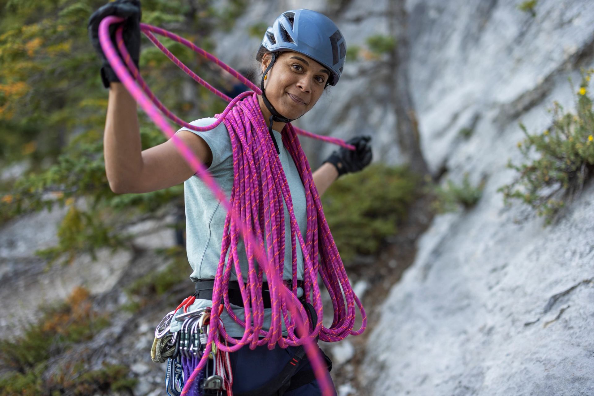 Women with helmet on looking at camera as she loops her climing rope over her shoulders