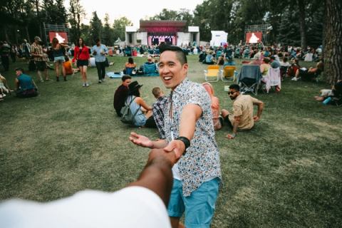 A couple / two men holding hands at an outdoor festival from the POV of the one man