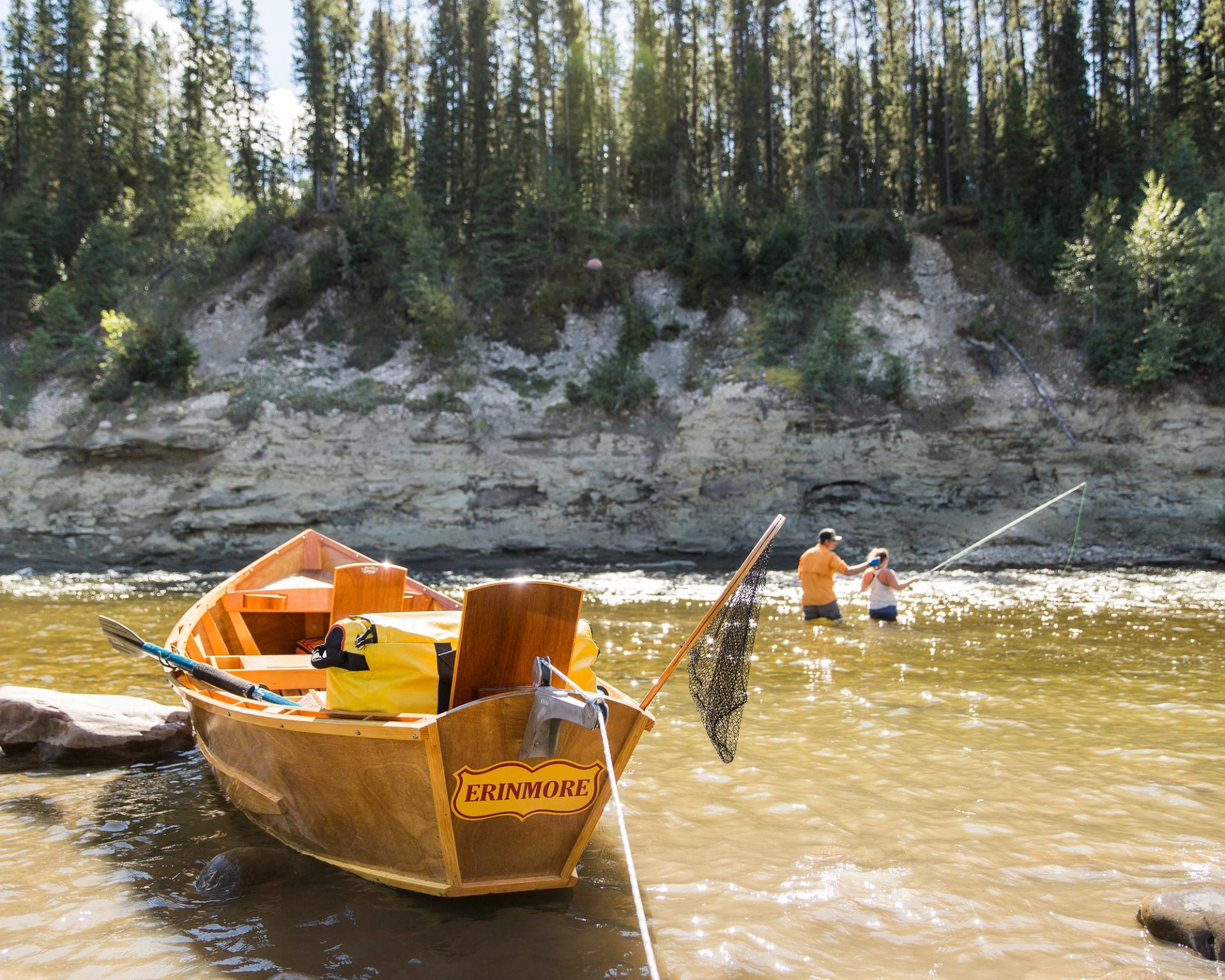 Couple learning to fly fish in a river with a boat in the foreground