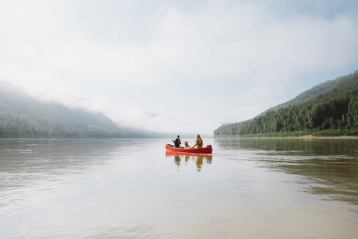 Couple with dog paddling canoe in Peace River