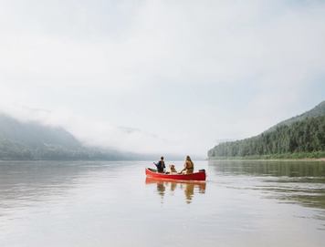 Couple with dog paddling canoe in Peace River