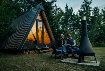 Two people roast marshmallows at Pine Creek Retreat in front of an A-frame cabin.