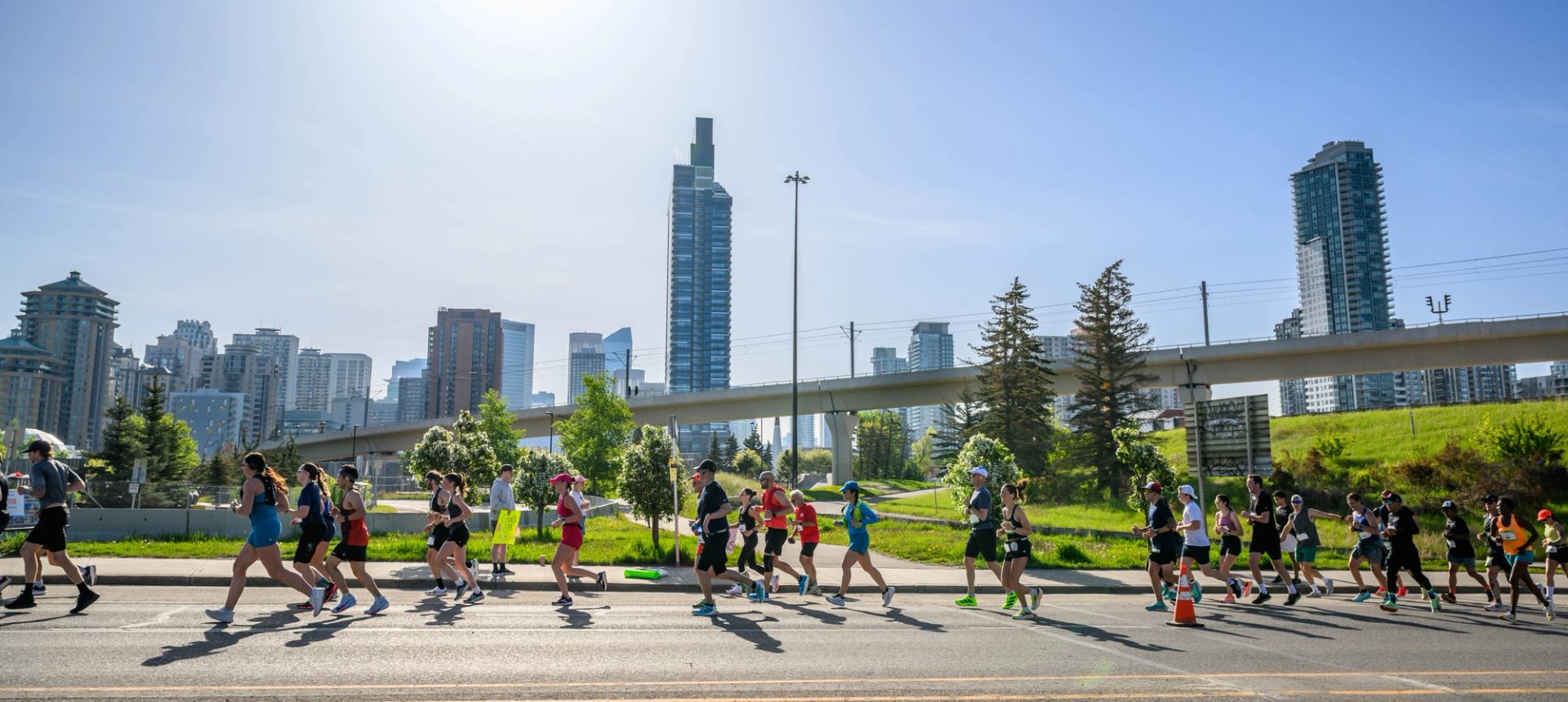 Dozens of runners pass Calgary’s skyline and downtown greenspace during the Calgary Marathon weekend.