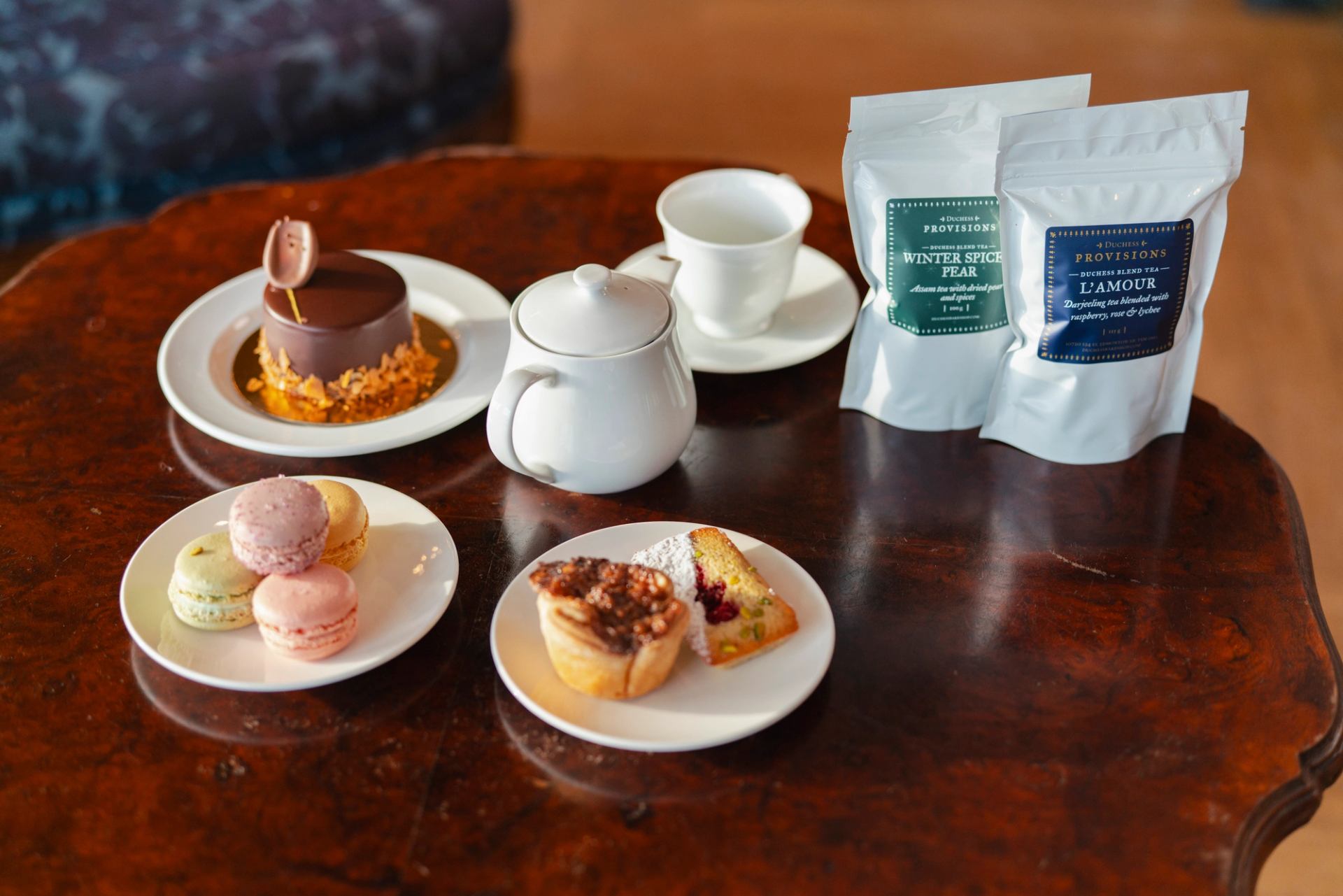 Macarons and other elegant desserts alongside a pot of tea and tea bags at Duchess Bake Shop.