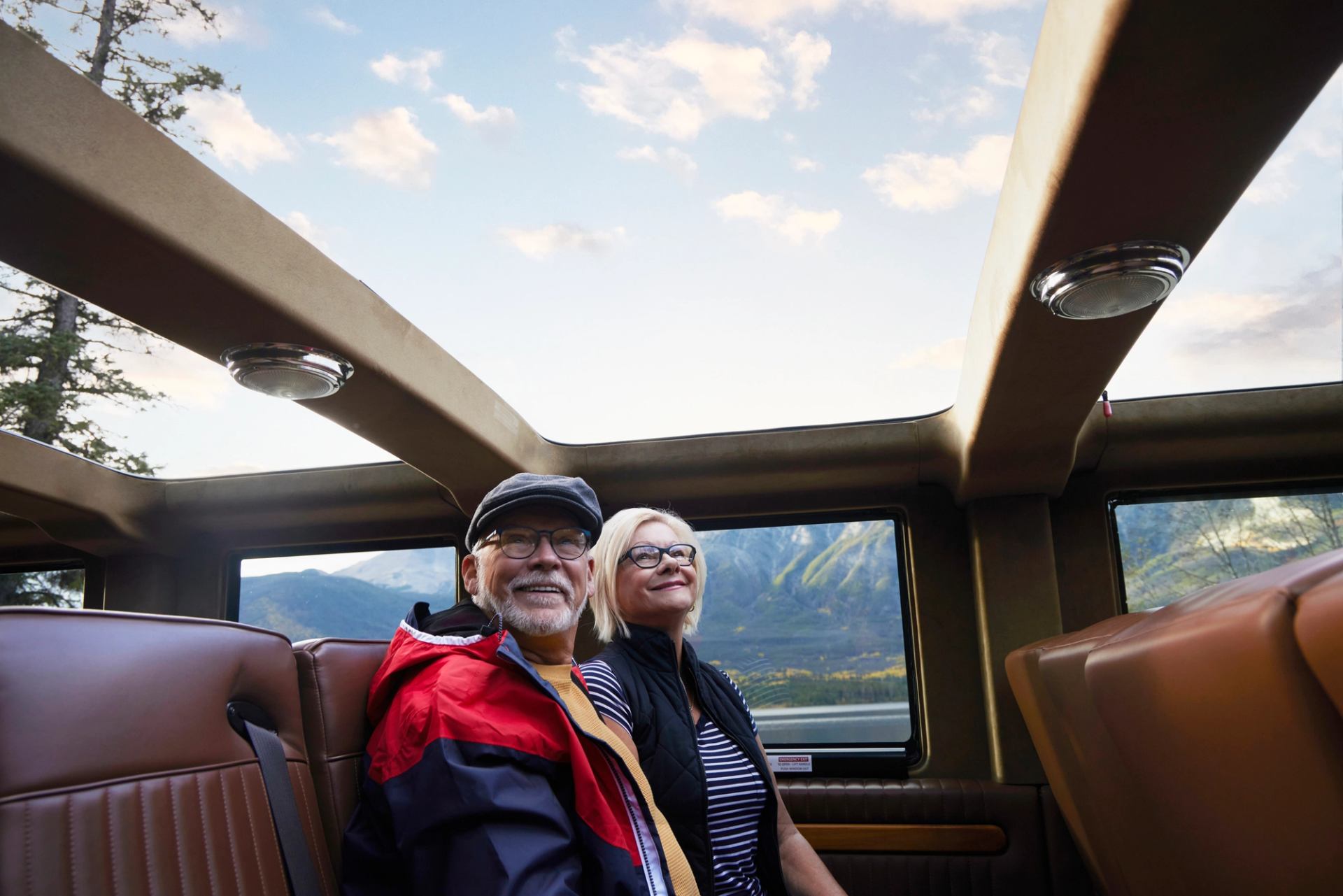 A couple in an open top touring bus in the Canadian Rockies.