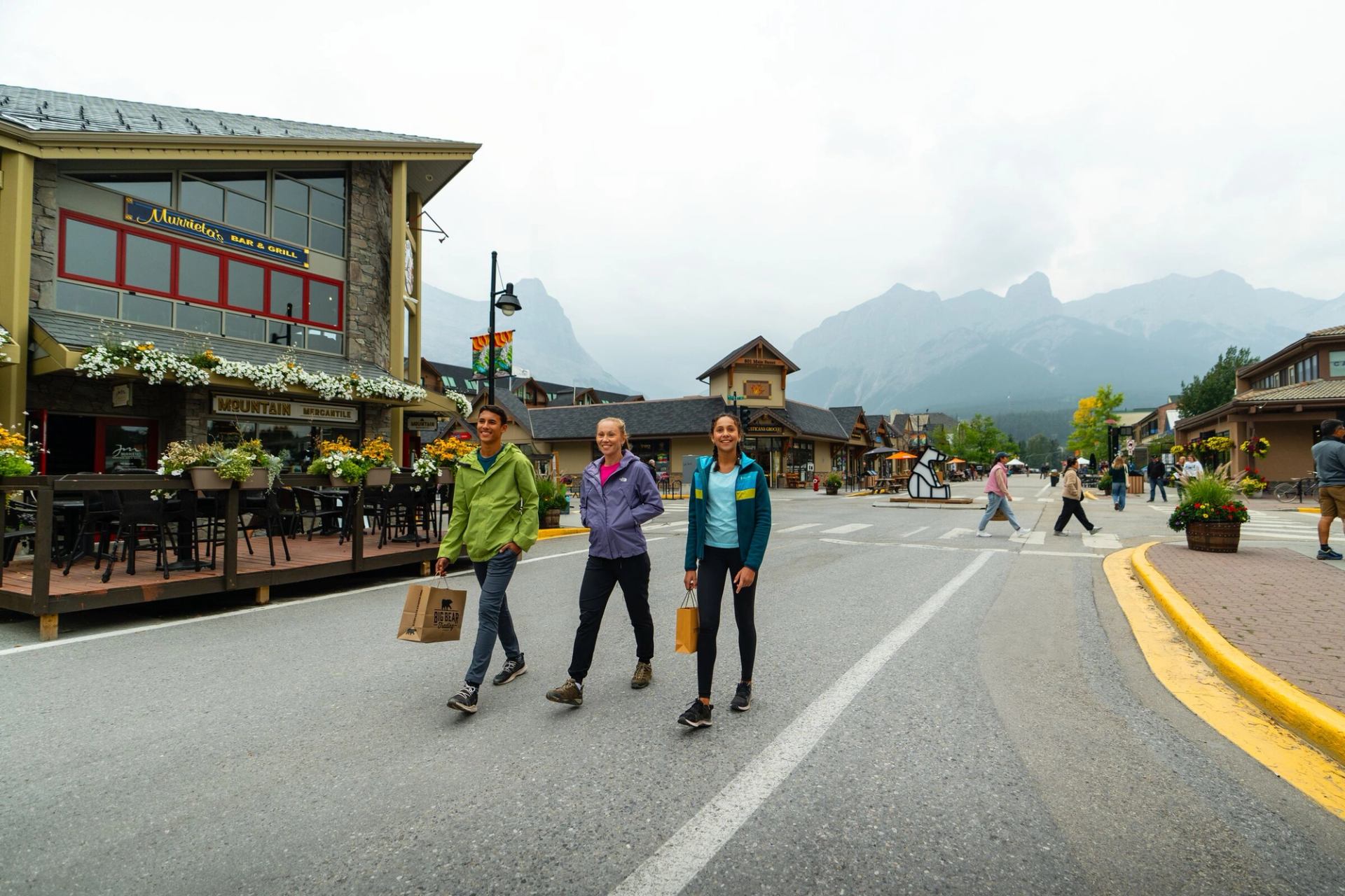 A family walks through downtown Canmore, carrying shopping bags from local Canmore stores.