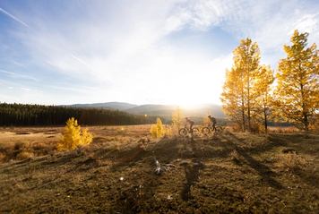Two people mountain biking in the Foothills during autumn.