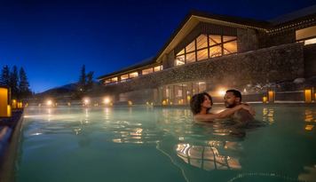 Couple enjoying the Fairmont Jasper Park Lodge outdoor pool at dusk.