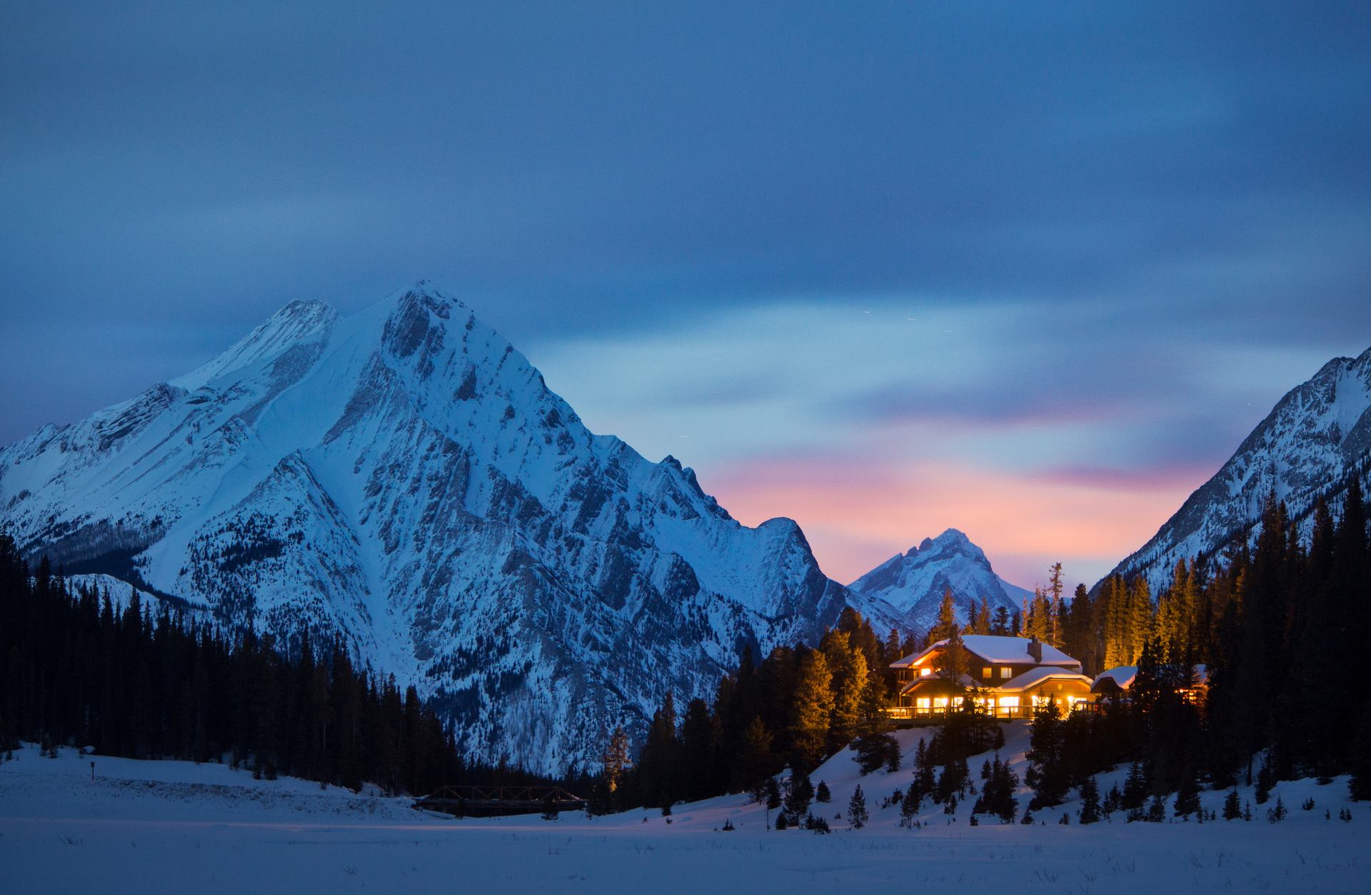 A nighttime image of Mount Engadine Lodge with mountains in the background.