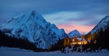 A nighttime image of Mount Engadine Lodge with mountains in the background.