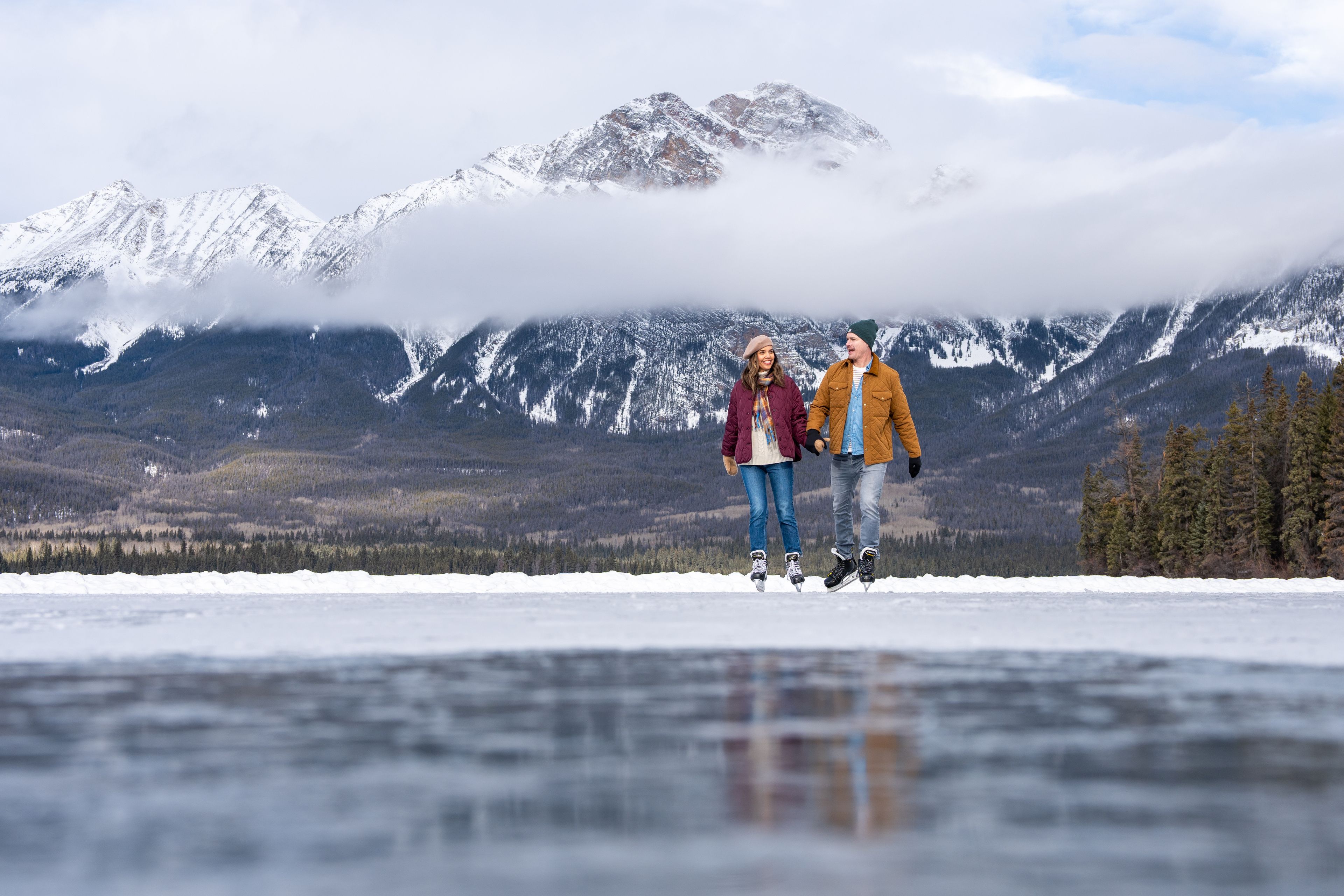 A couple skating on a lake in Jasper.