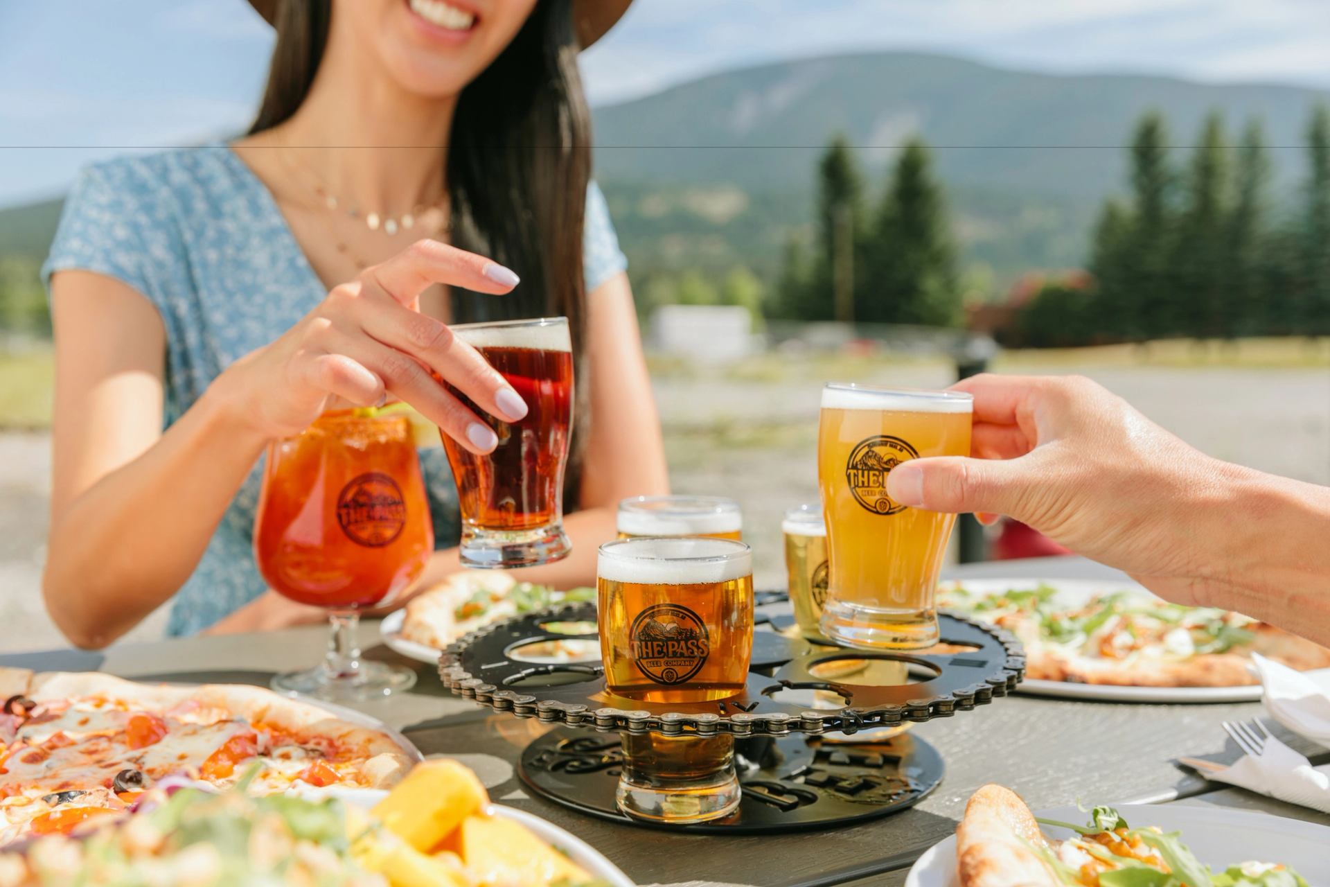 People have beer and pizza on a patio.