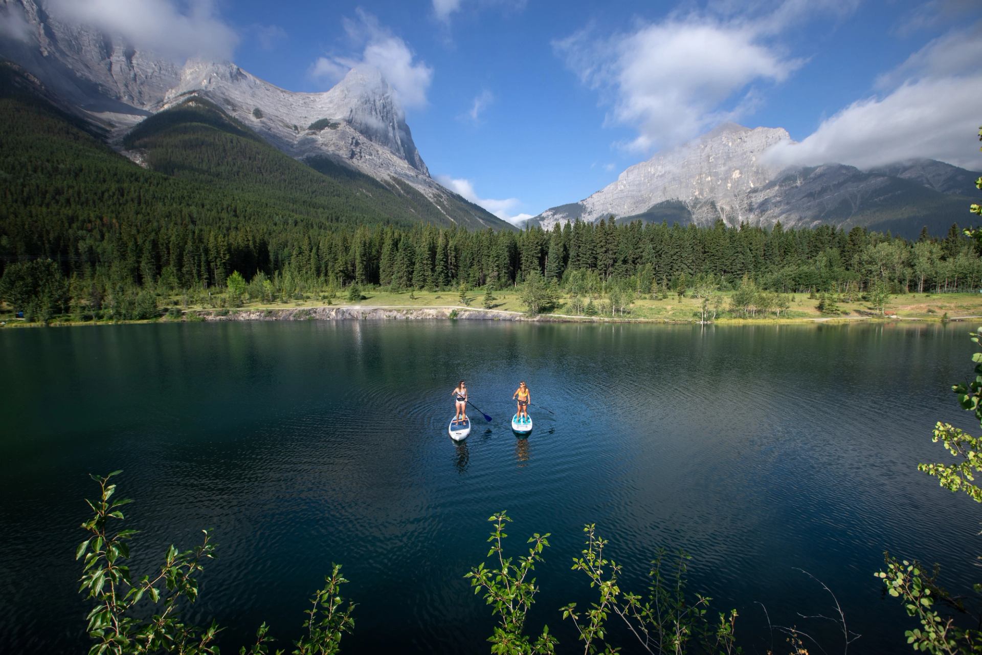 Friends stand up paddleboarding on Quarry Lake in Kananaskis Country