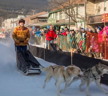 Spectators watching the dog sledding race through a town street.