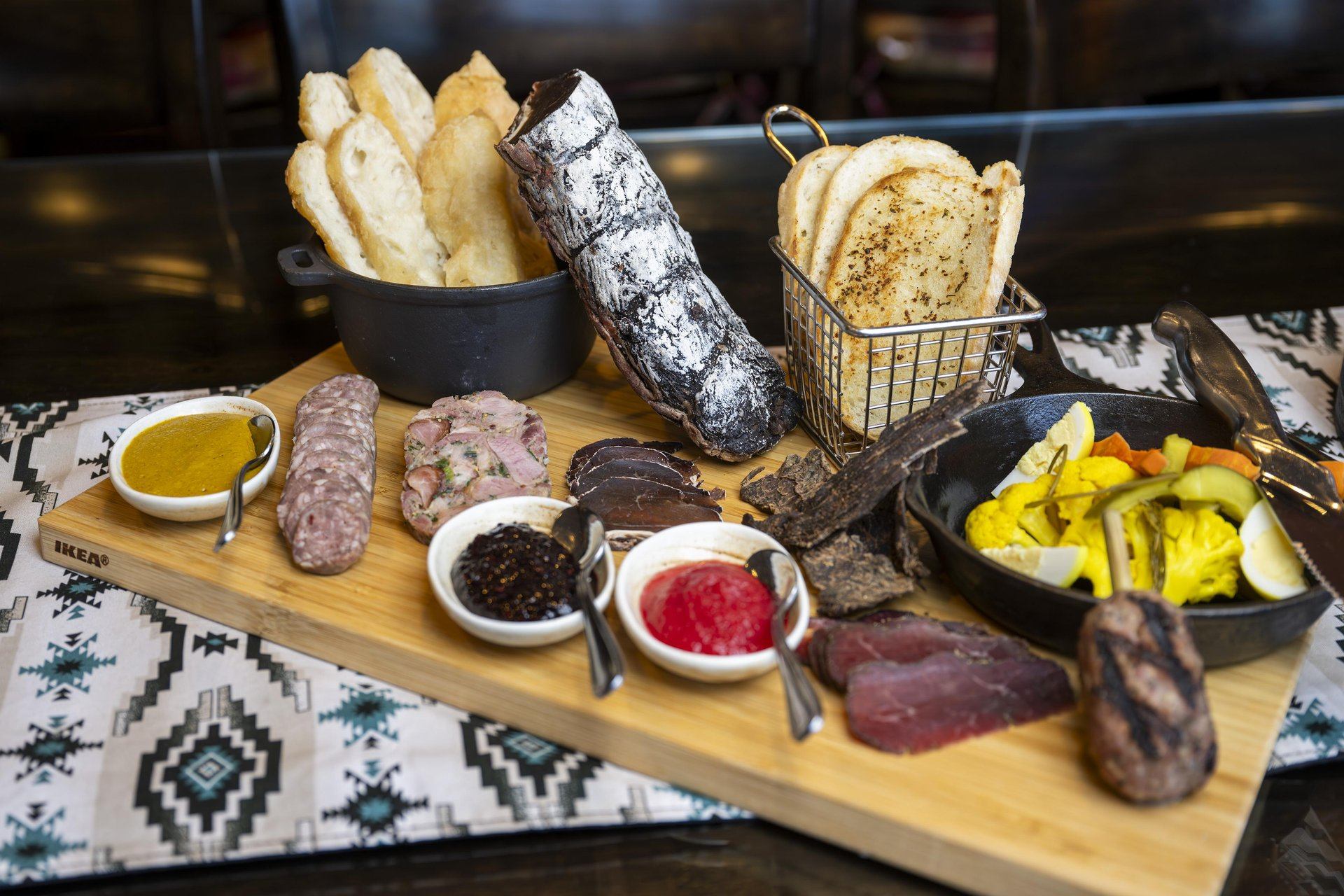 A charcuterie board with preserved meats, spreads, pickled vegetables, bannock and fry bread.