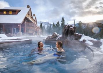Two women enjoying the hot tub at the Hidden Ridge resort in front of the Canadian Rockies