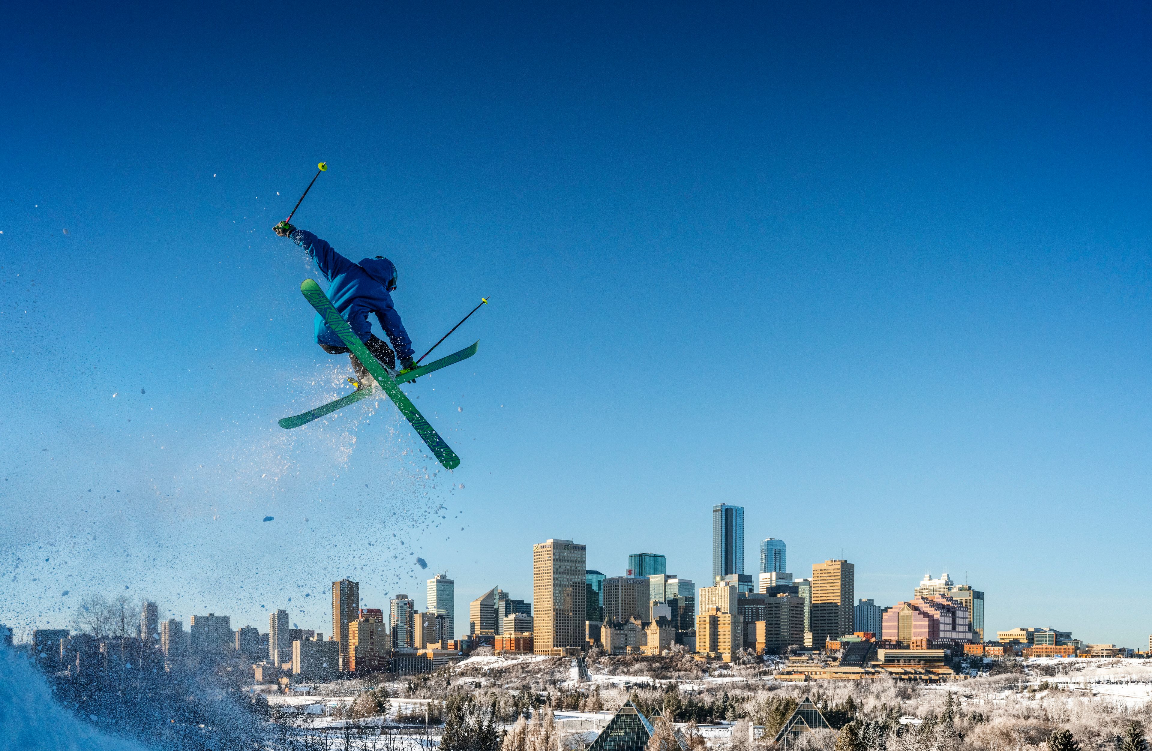 A skier pulls a trick with Edmonton's skyline in the distance.