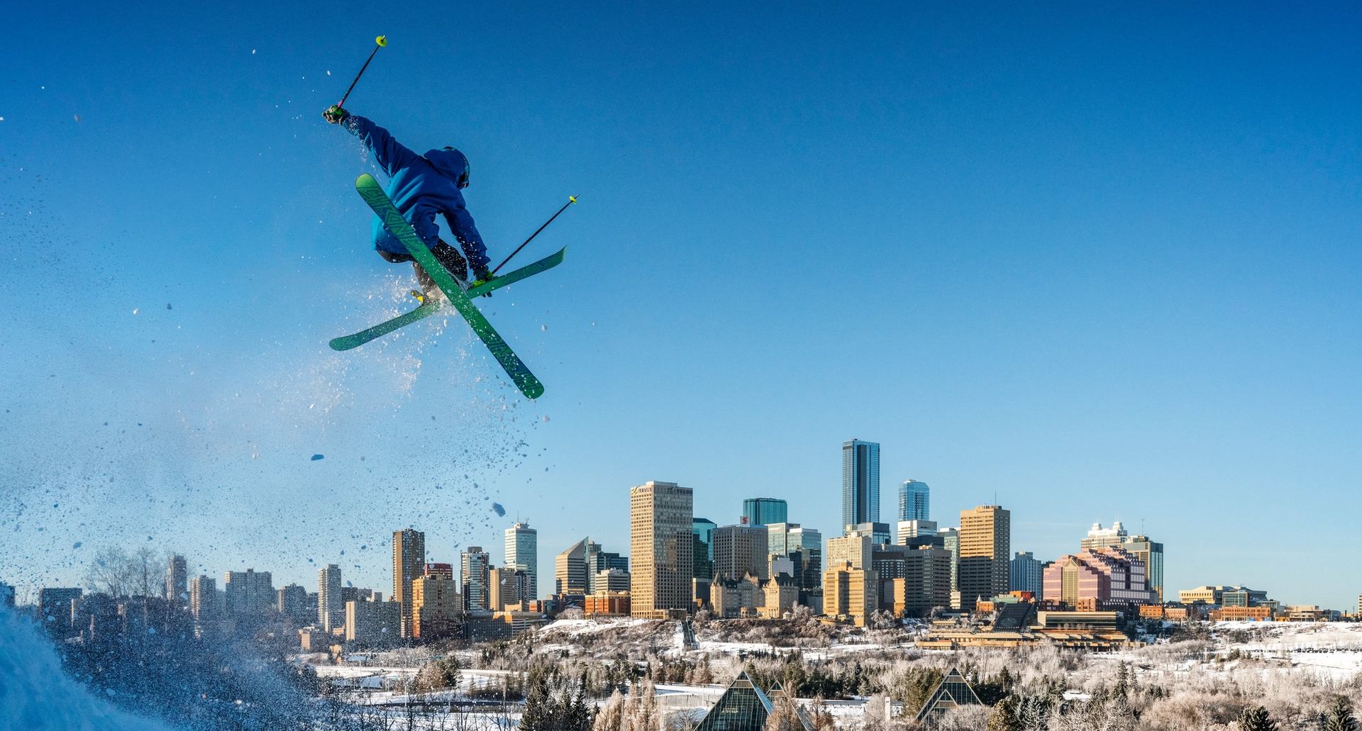 Person ski jumping with downtown Edmonton in background