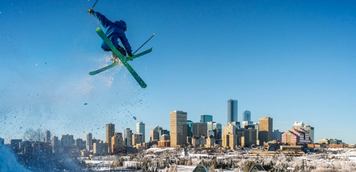 A skier pulls a trick with Edmonton's skyline in the distance.