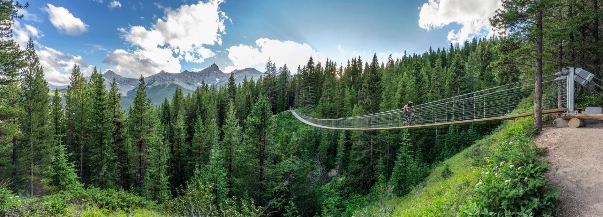 Mountain biking crossing the Blackshale Suspension Bridge in Kananaskis