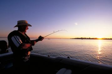 Scenic shot of man fishing at Lesser Slave Lake at sunset