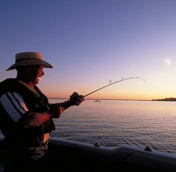 Scenic shot of man fishing at Lesser Slave Lake at sunset