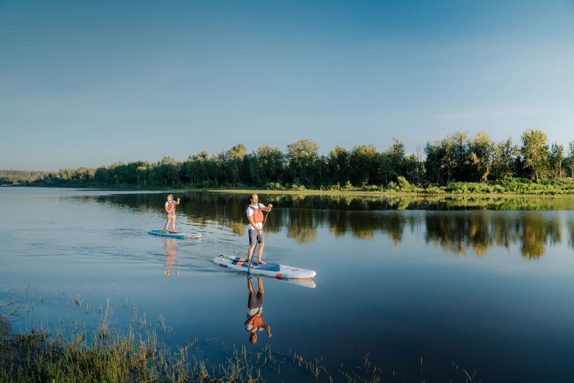 Two people on stand up paddle boards on Syne River near Fort McMurray.