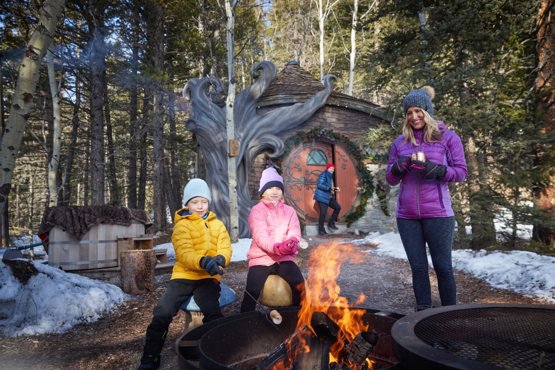 A family roasts marshmallows in a fire pit in front of their cottage at Charmed Resorts.