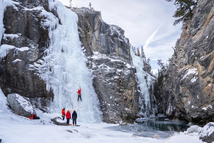 A wide shot of a group Ice climbing in canyon