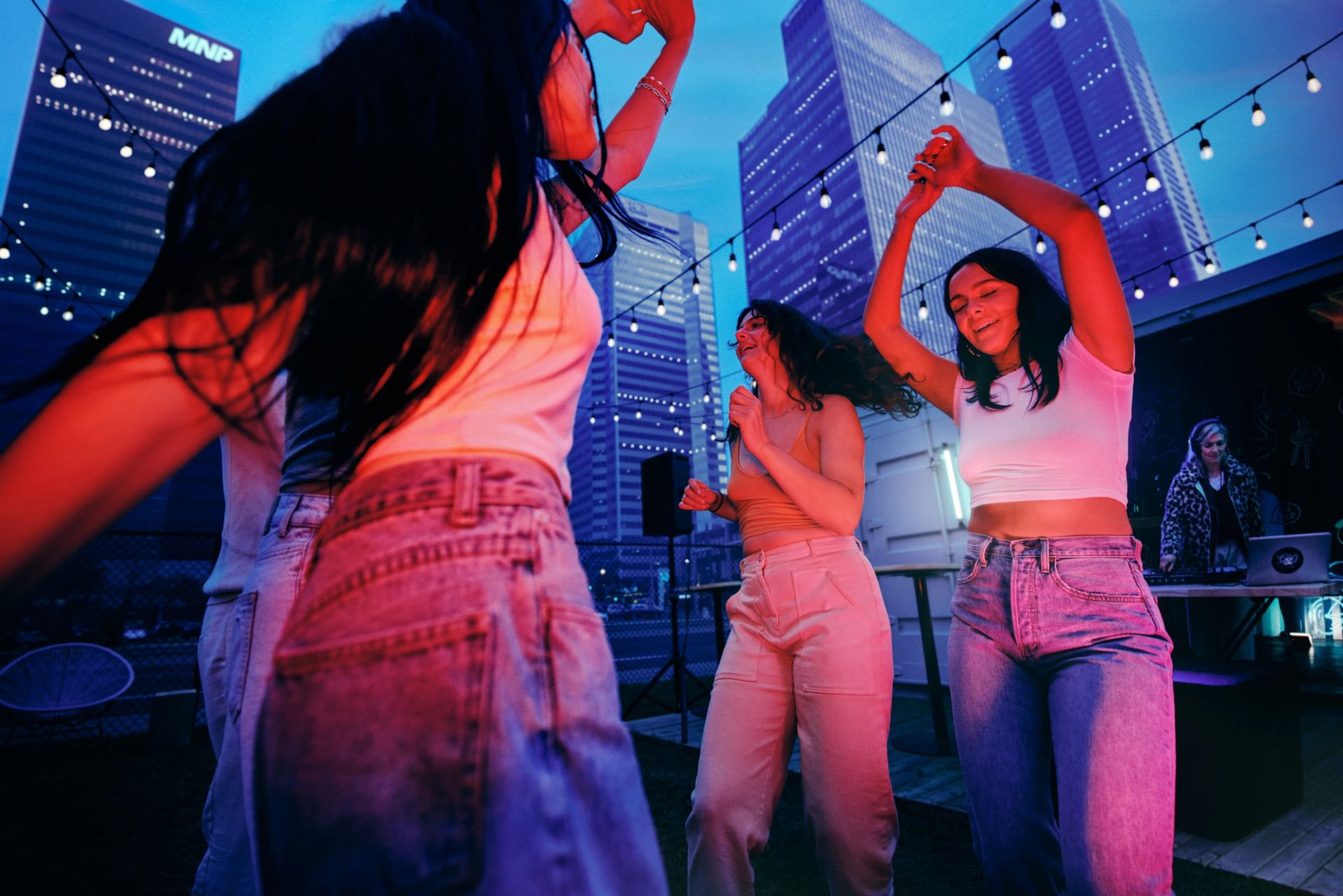 A group of friends dancing under string lights at The Backyard in downtown Edmonton.