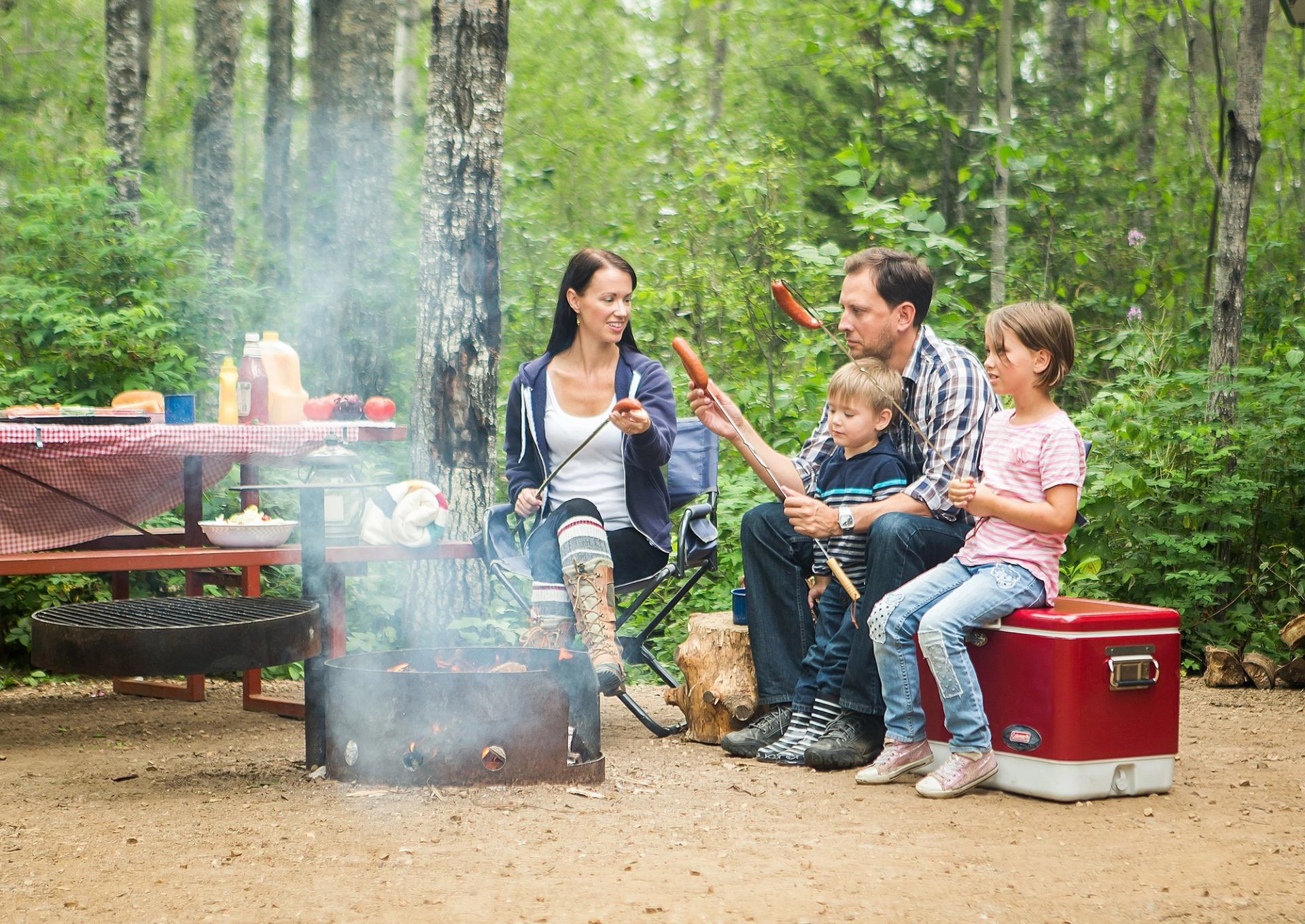 Family roasting hotdogs on a campfire in the campground at Lesser Slave Lake Provincial Park.