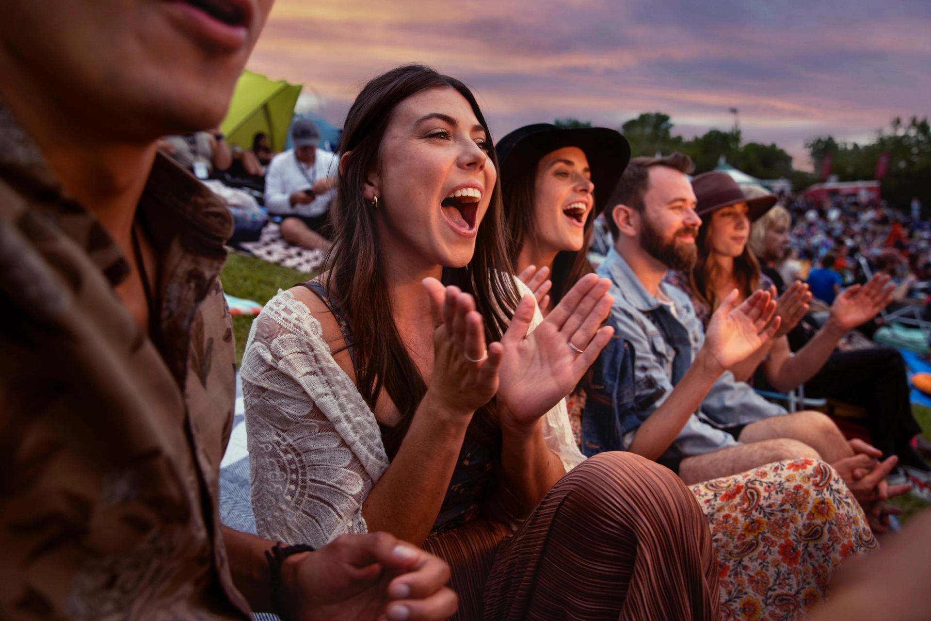 A group of people clapping and cheering at the Edmonton Folk Music Festival.