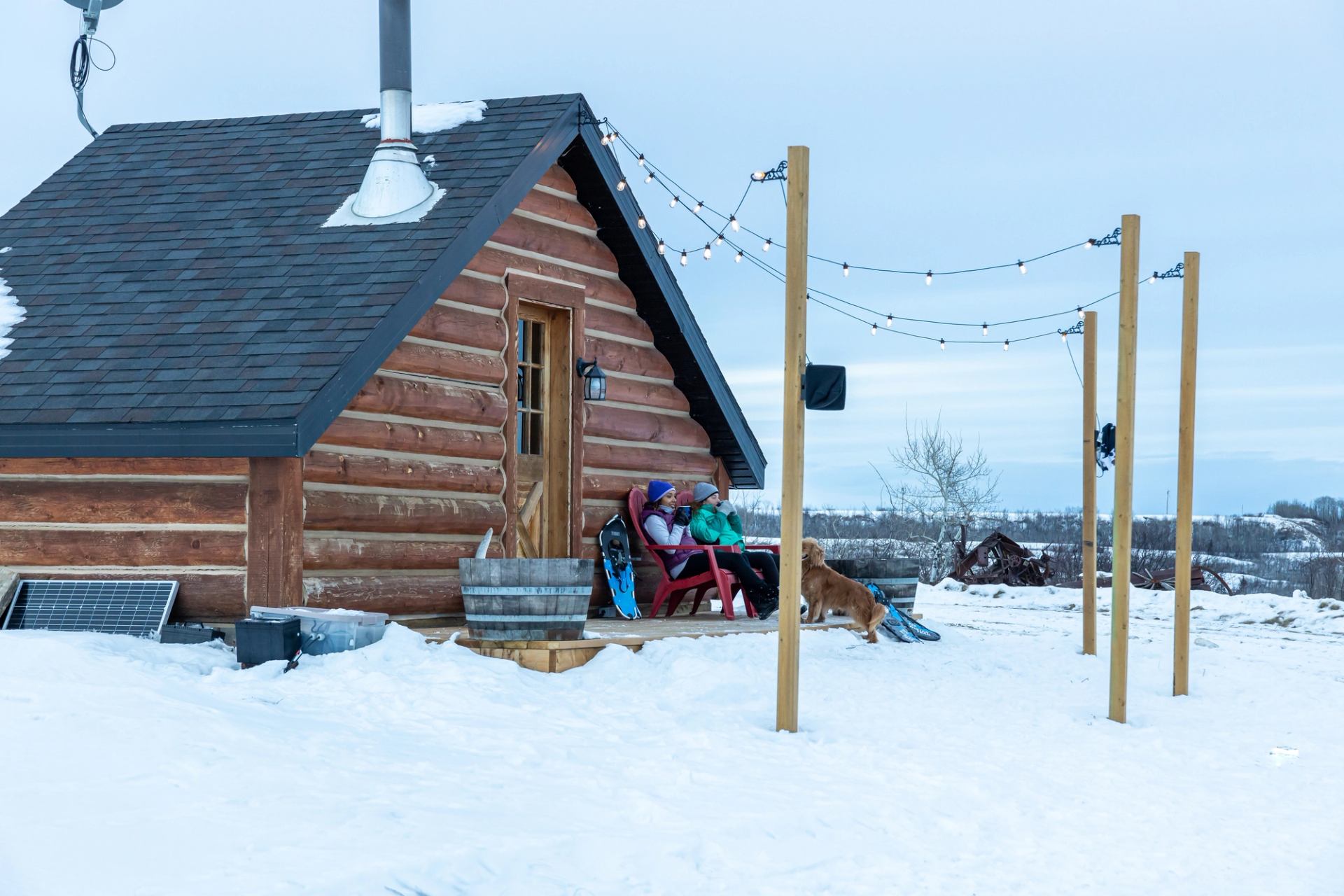 People sitting outside of a log cabin in winter