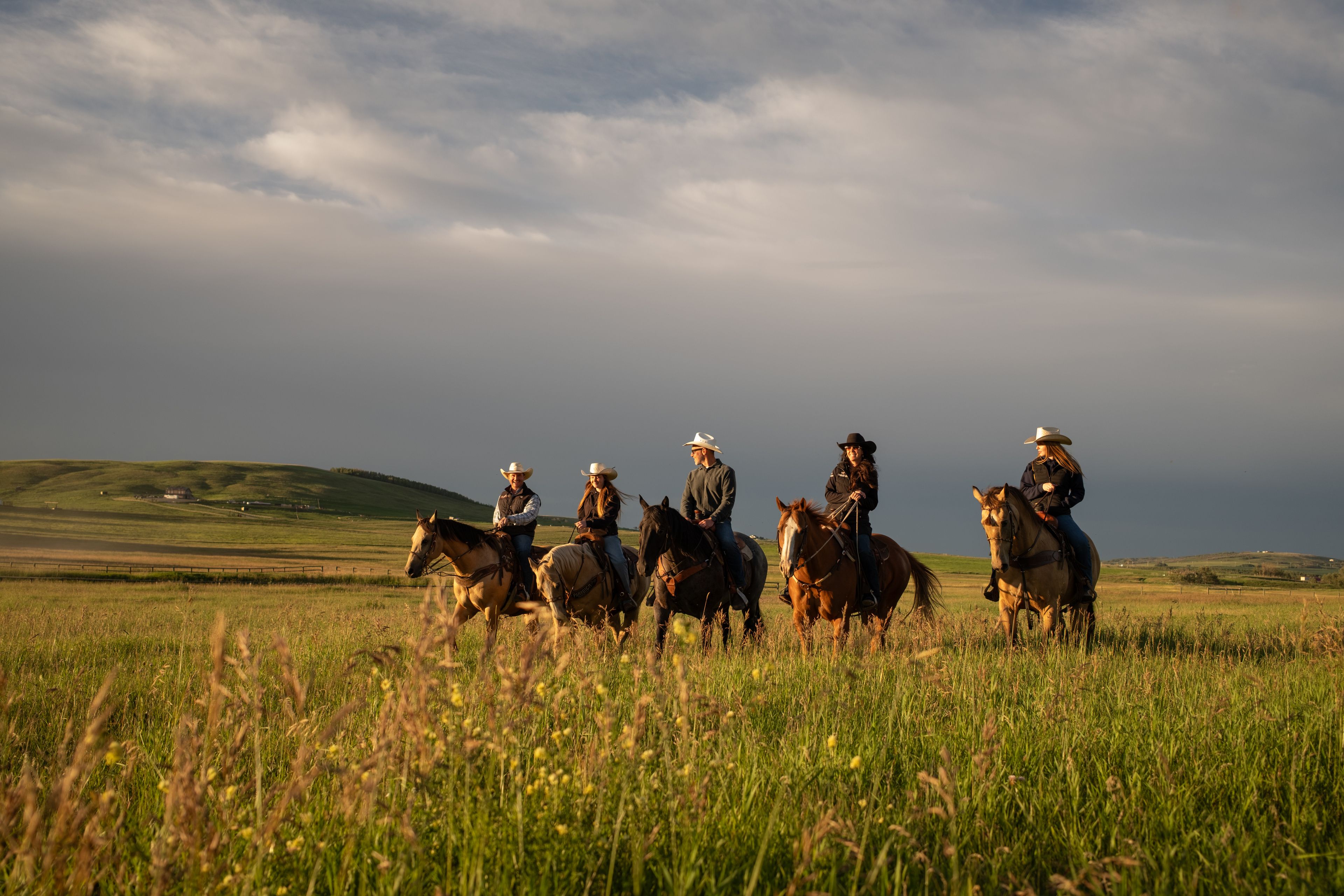 A family ride on horseback in rolling hillside near Millarville.