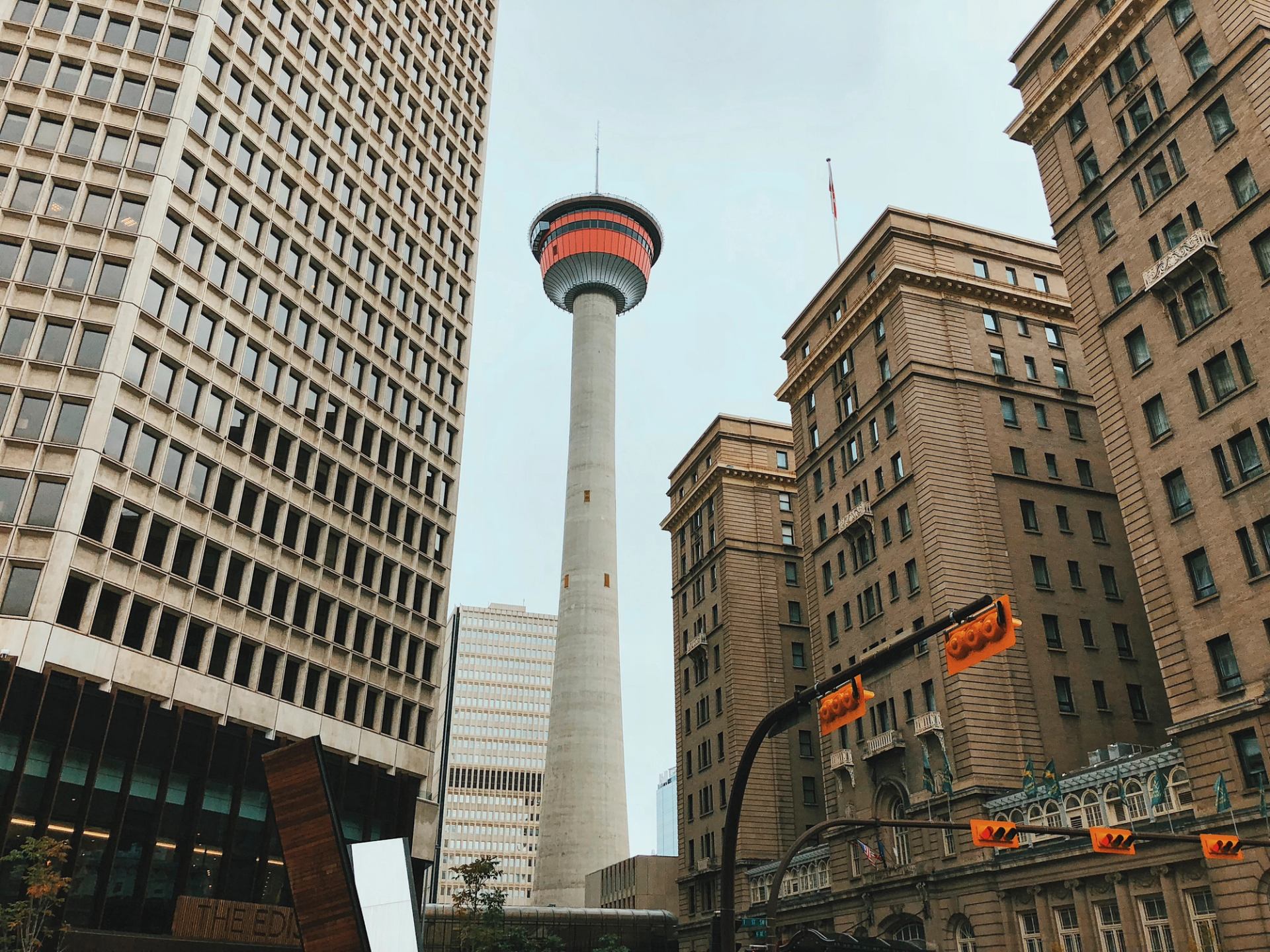 A view from the ground of the Calgary Tower surrounded by downtown buildings