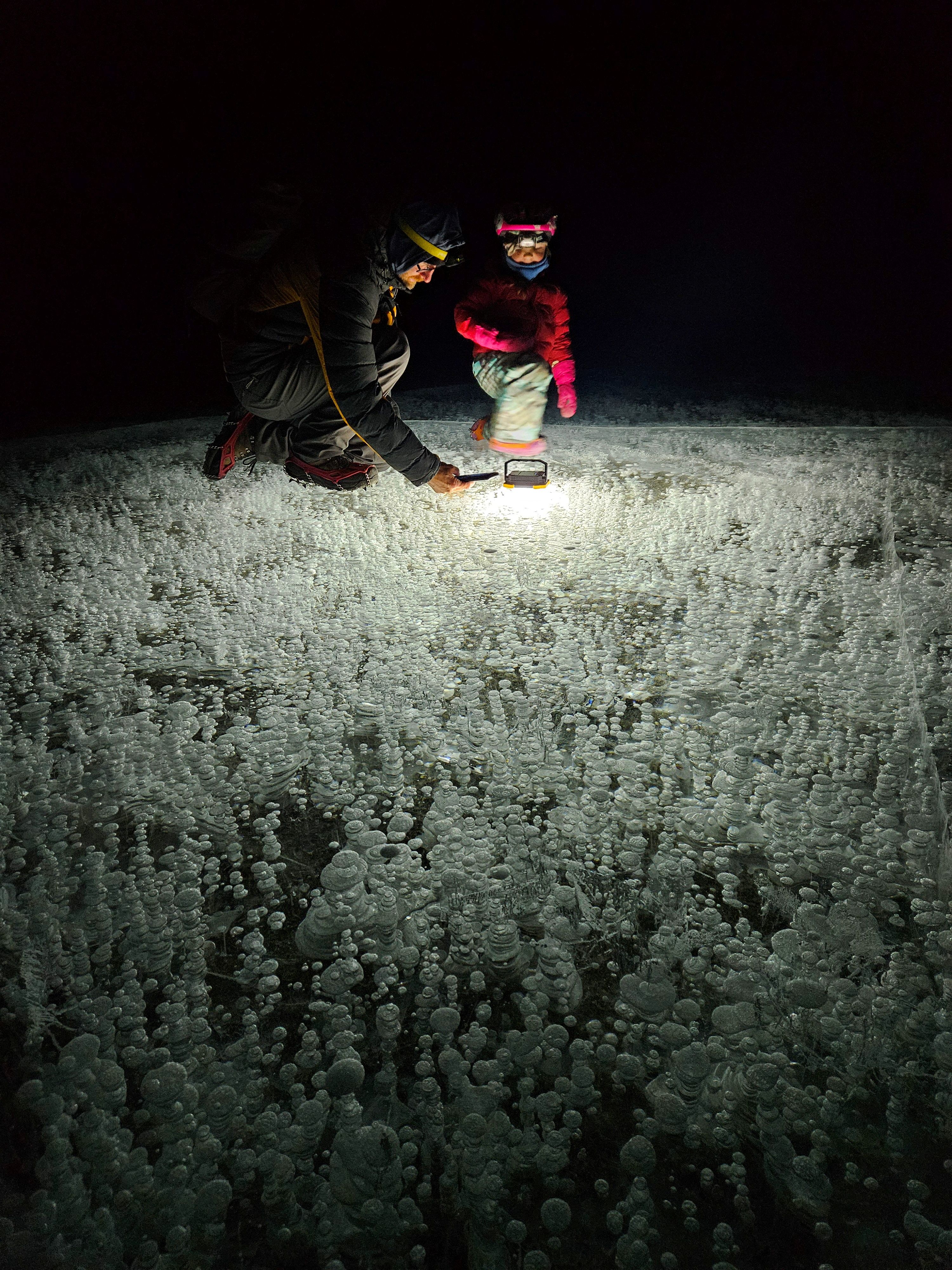 A guide lights up the bubbles on Abraham Lake at night.