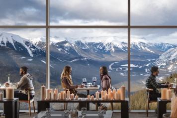 Guests dining at the Sky Bistro at the top of the Banff Gondola with mountain views outside the window.