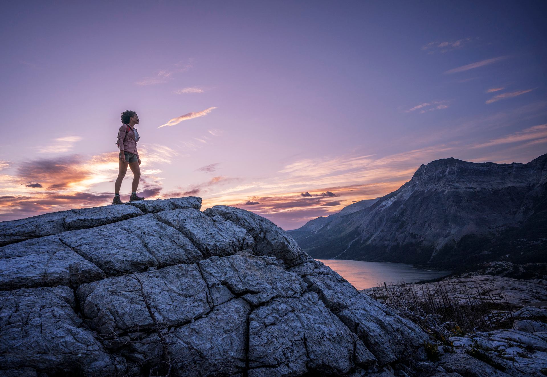 A woman stands on Bear's Hump overlooking Waterton.