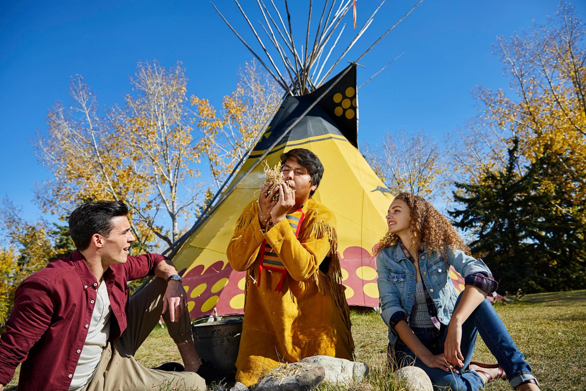 People learn how to make fire from an Indigenous interpreter at Heritage Park.