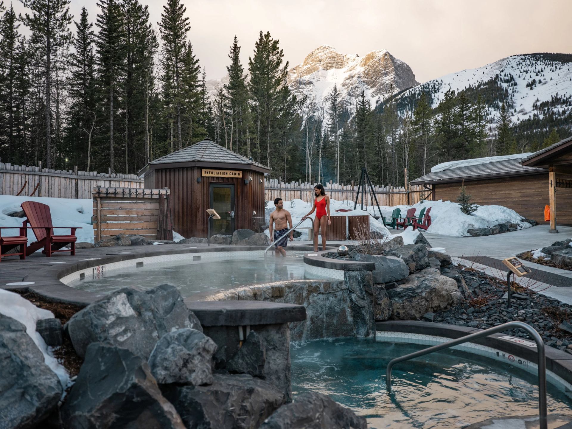 A couple enjoys the plunge pools at the Kananaskis Nordic Spa. Mountains are seen in the background.