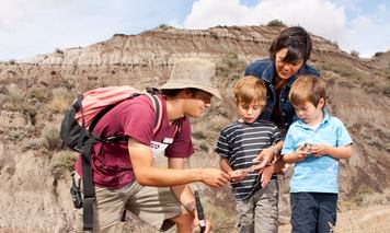 A tour guide showing a mother and two young children a fossil.