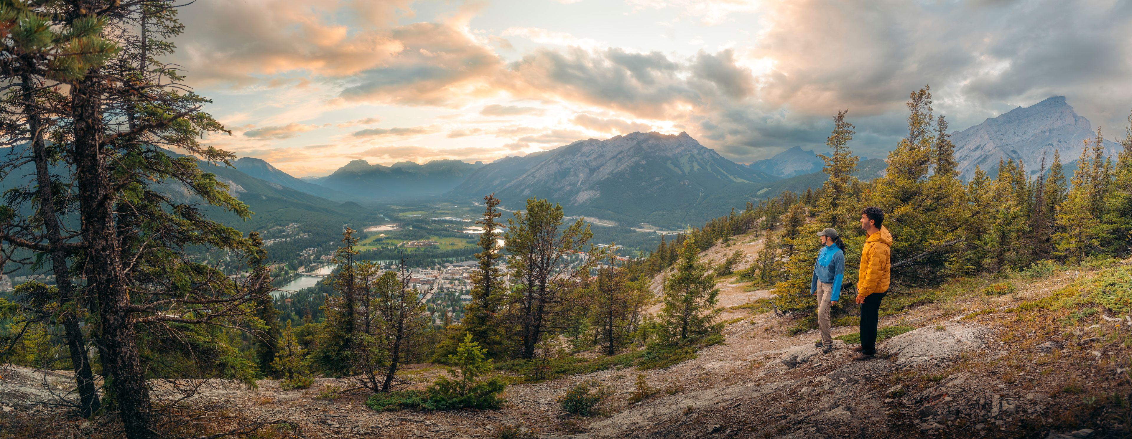 A pano shot of two hikers overlooking the view of Banff from Tunnel Mountian.
