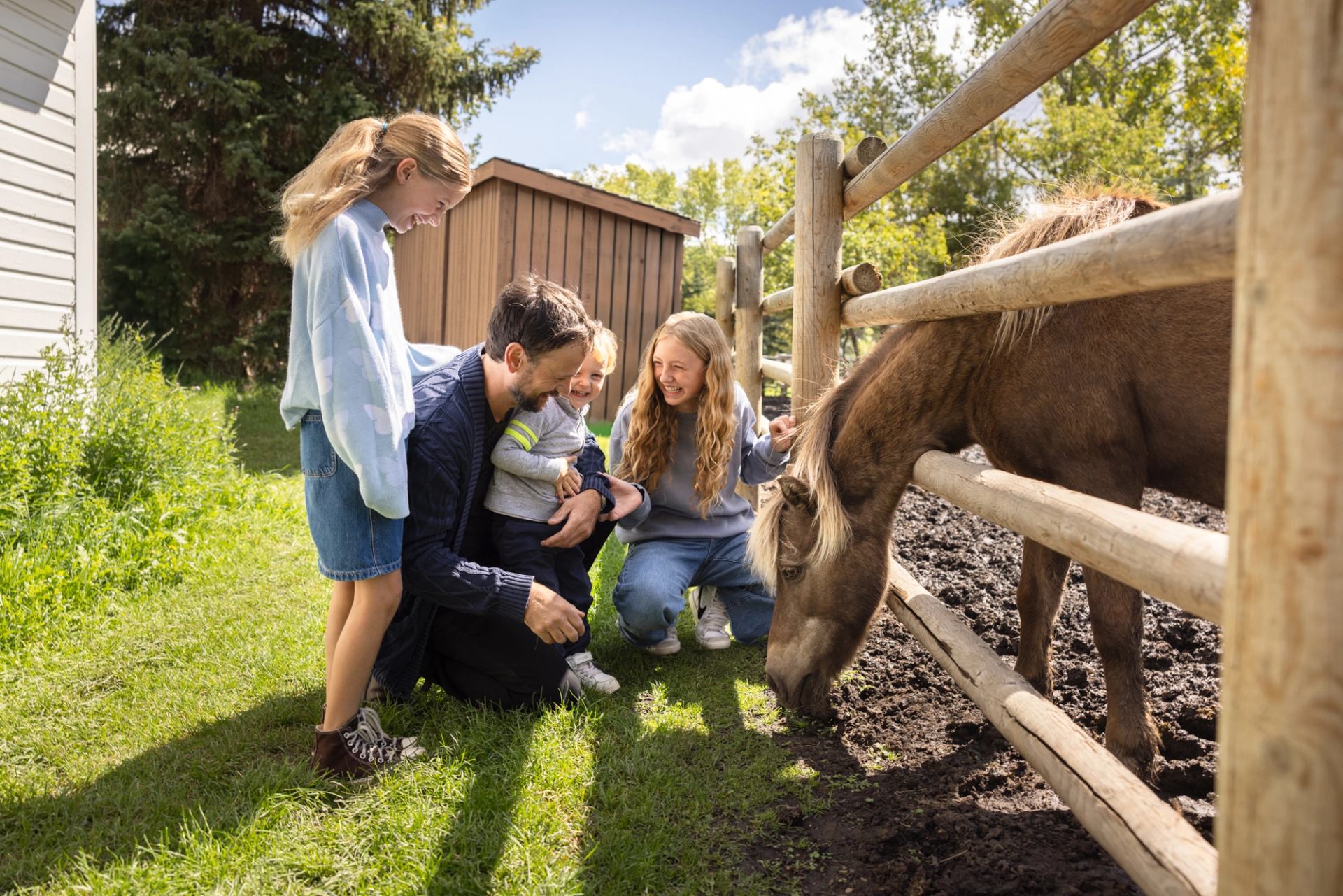 A family exploring Fort Edmonton and petting a horse.