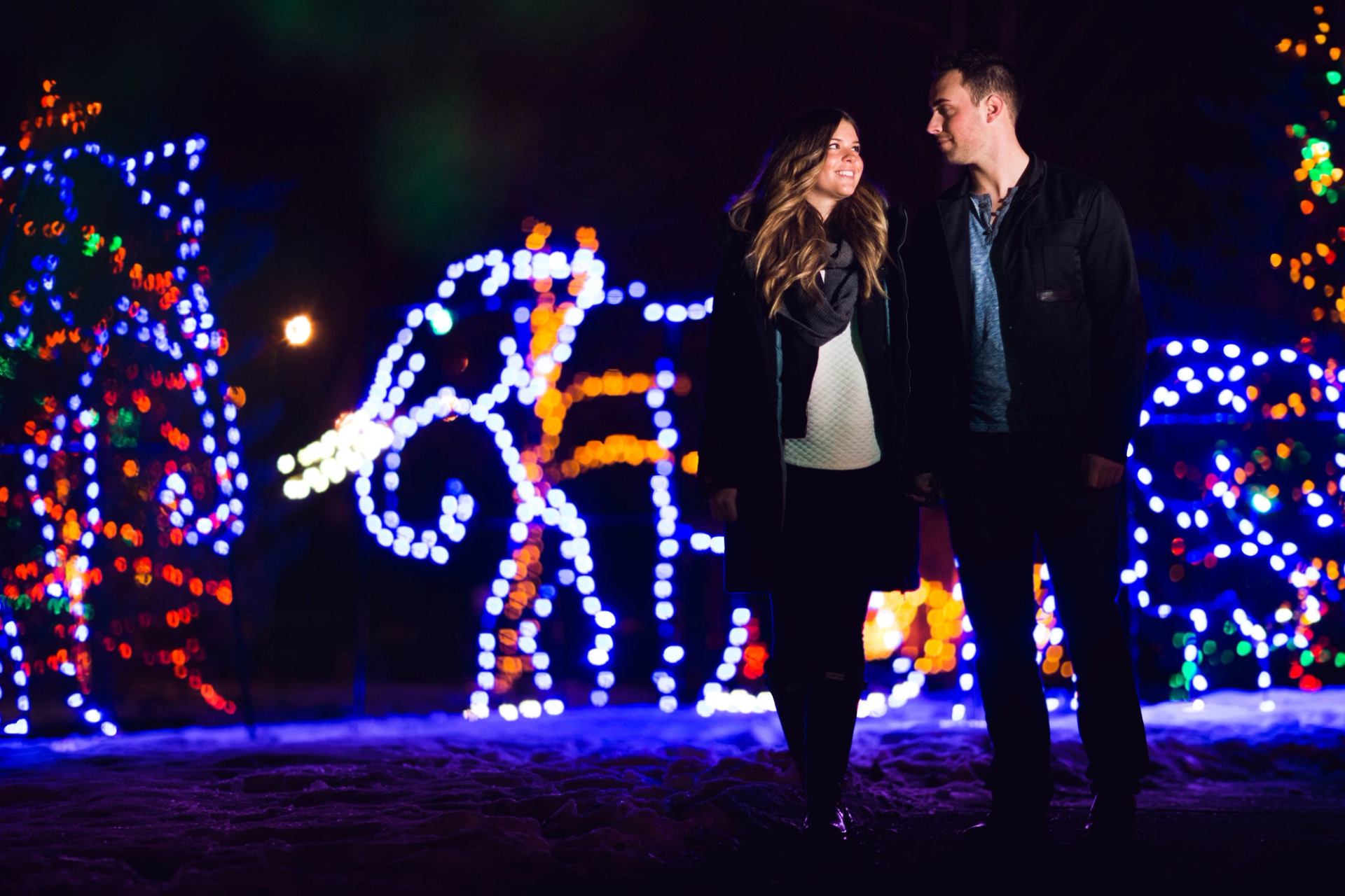 Couple walking through lit up   displays at night.