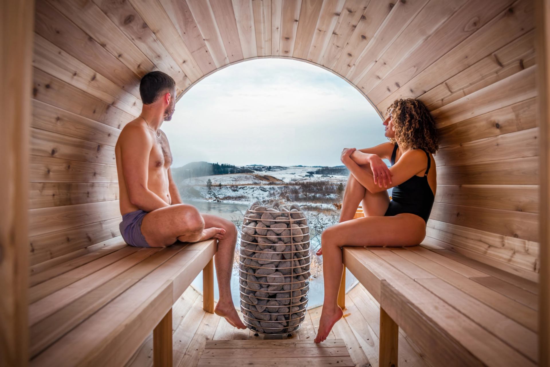A couple relax in a barrel sauna.