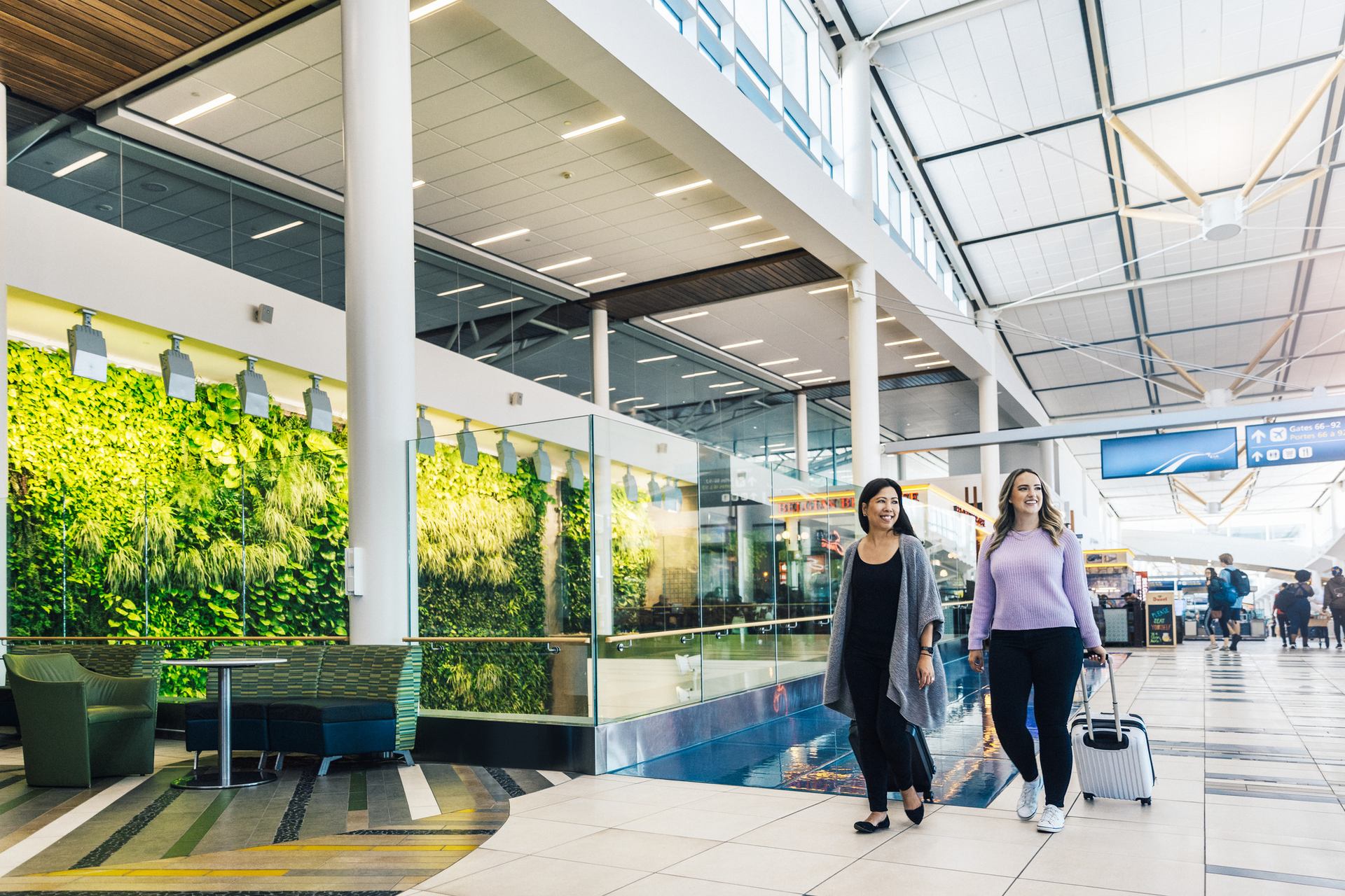 Two women walking with luggage through an airport