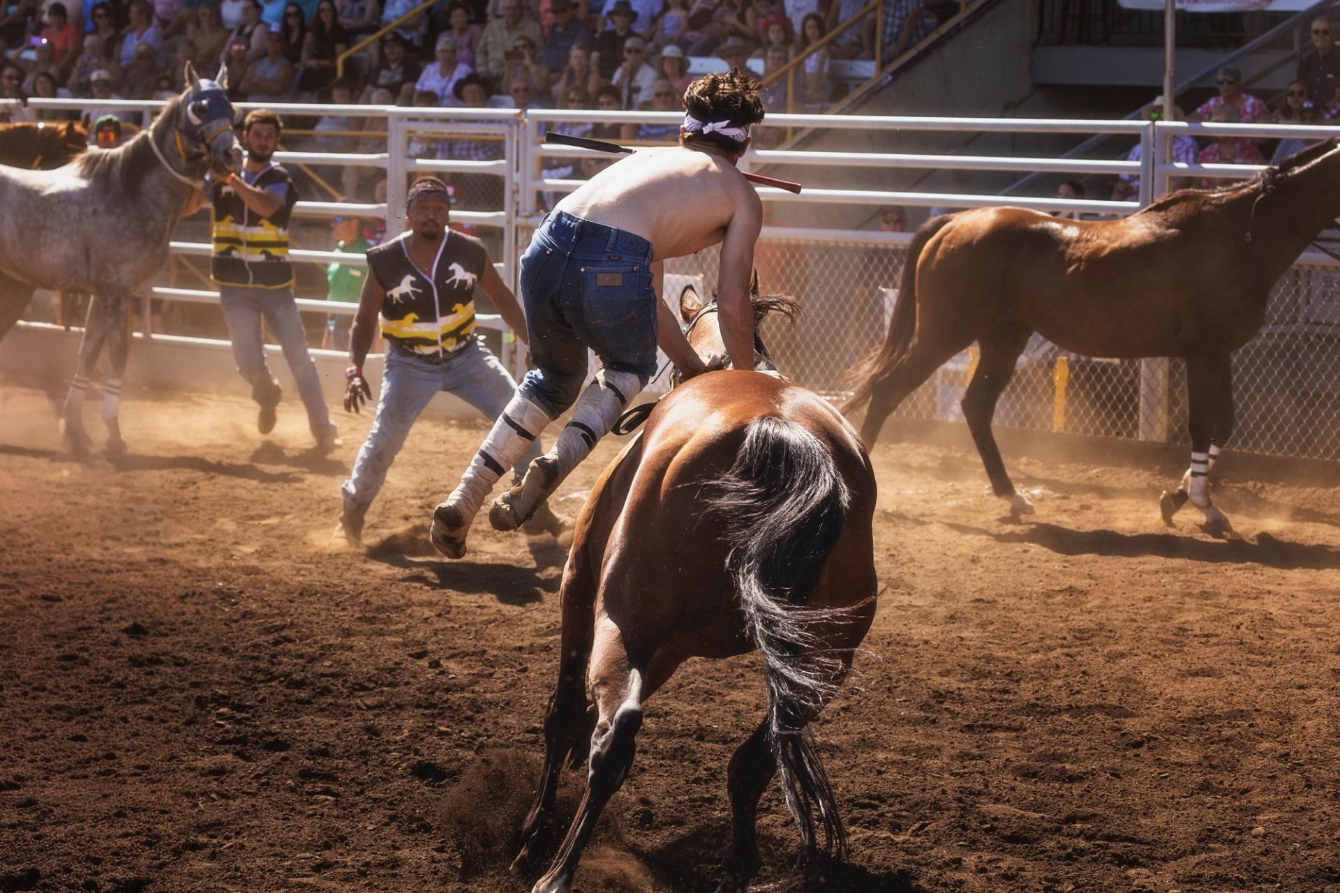 A rider leaps from his horse as part of the high-speed relay exchange while his teammates rush to catch the spent horse and hold the next one ready.