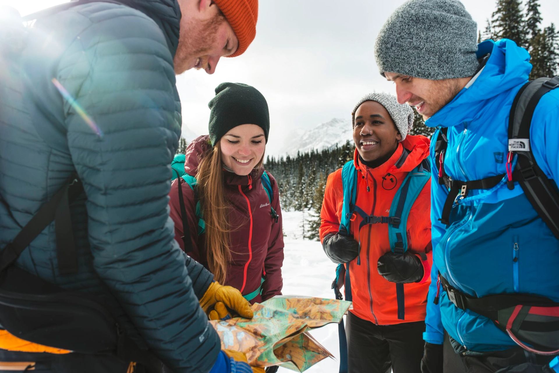 A group consults their trail map while winter hiking in Kananaskis Country.