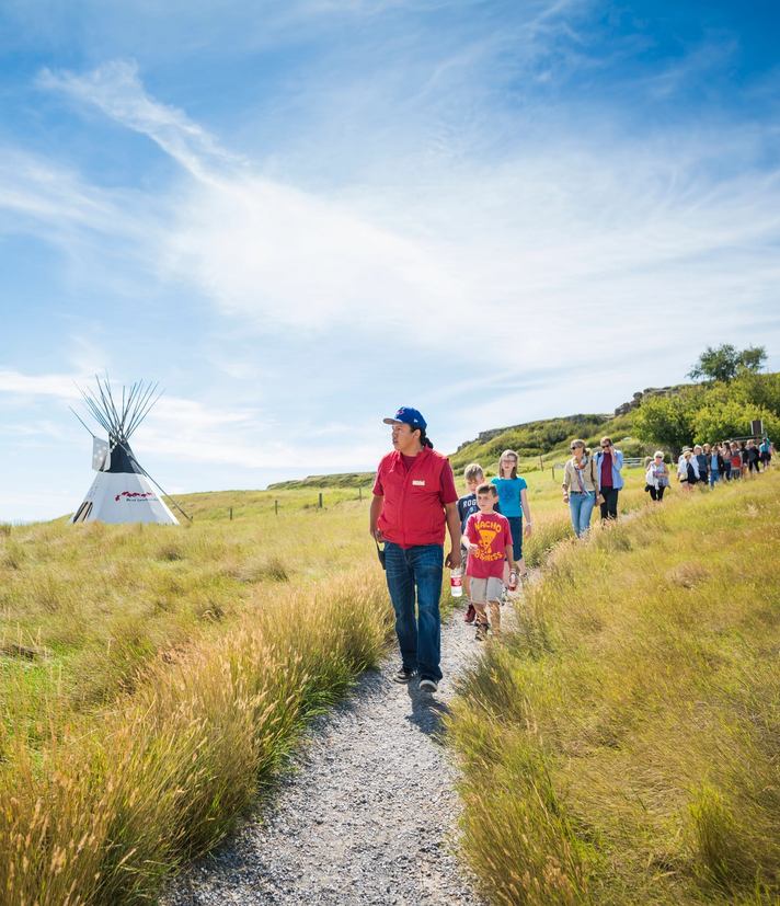 School group walking the pathways at Head-Smashed-In Buffalo Jump with an Indigenous guide.