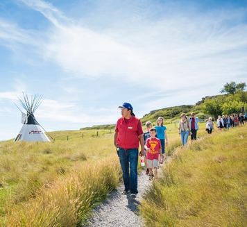 School group walking the pathways at Head-Smashed-In Buffalo Jump with an Indigenous guide.